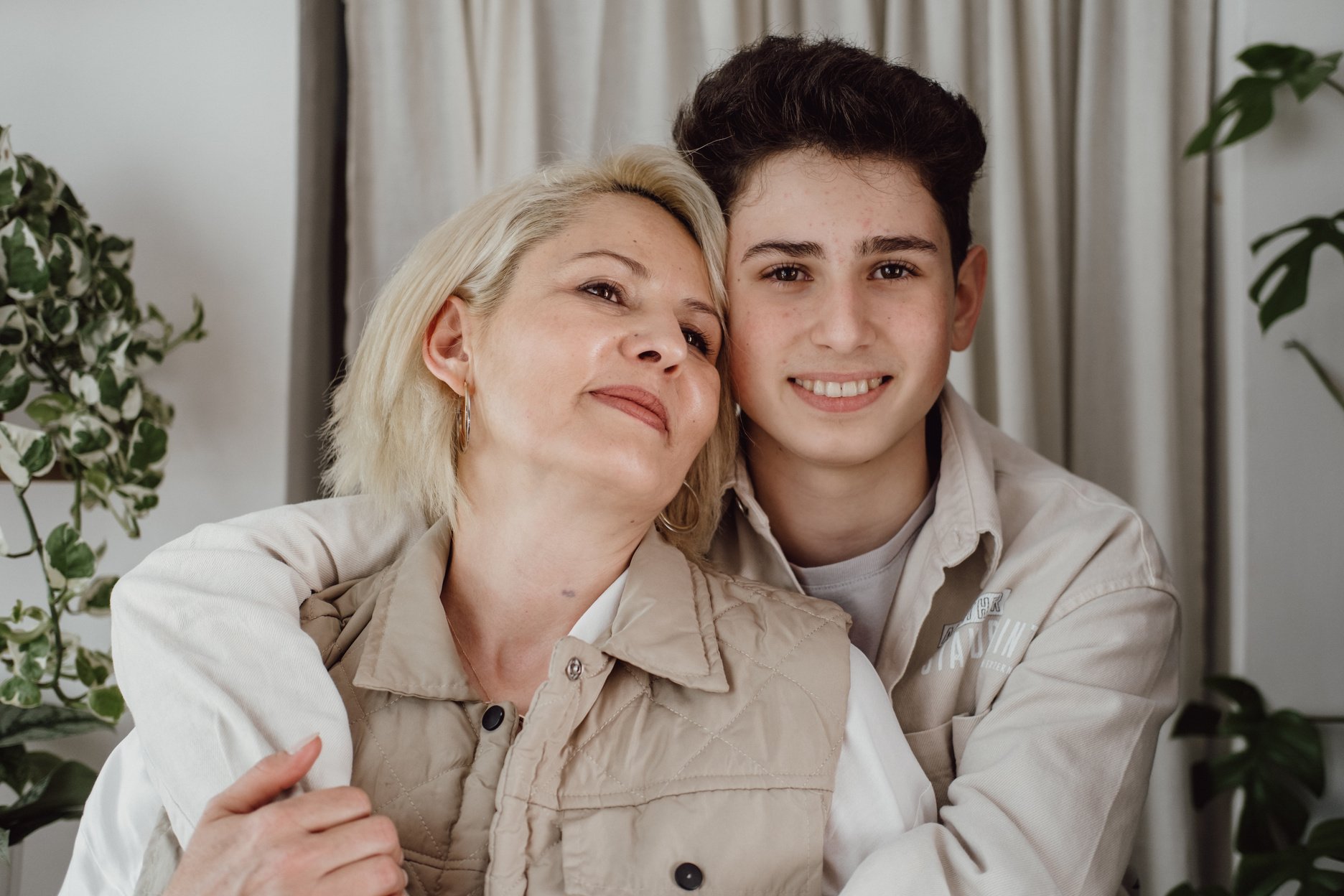 Smiling Teen Son Embracing His Mom Indoors